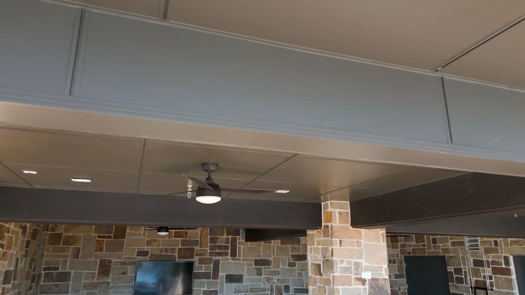 Interior ceiling with modern design, featuring a ceiling fan and stone wall accents.