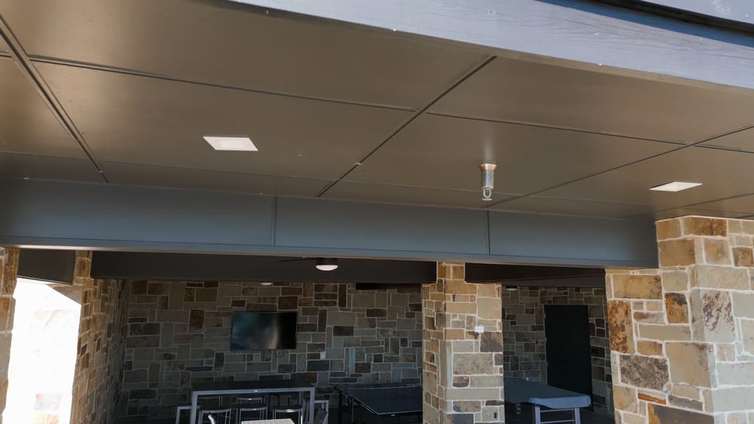 Modern outdoor patio with stone walls, ceiling lights, and an open layout.