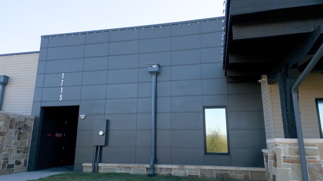 Modern commercial building exterior featuring dark paneling and large windows at 1715.