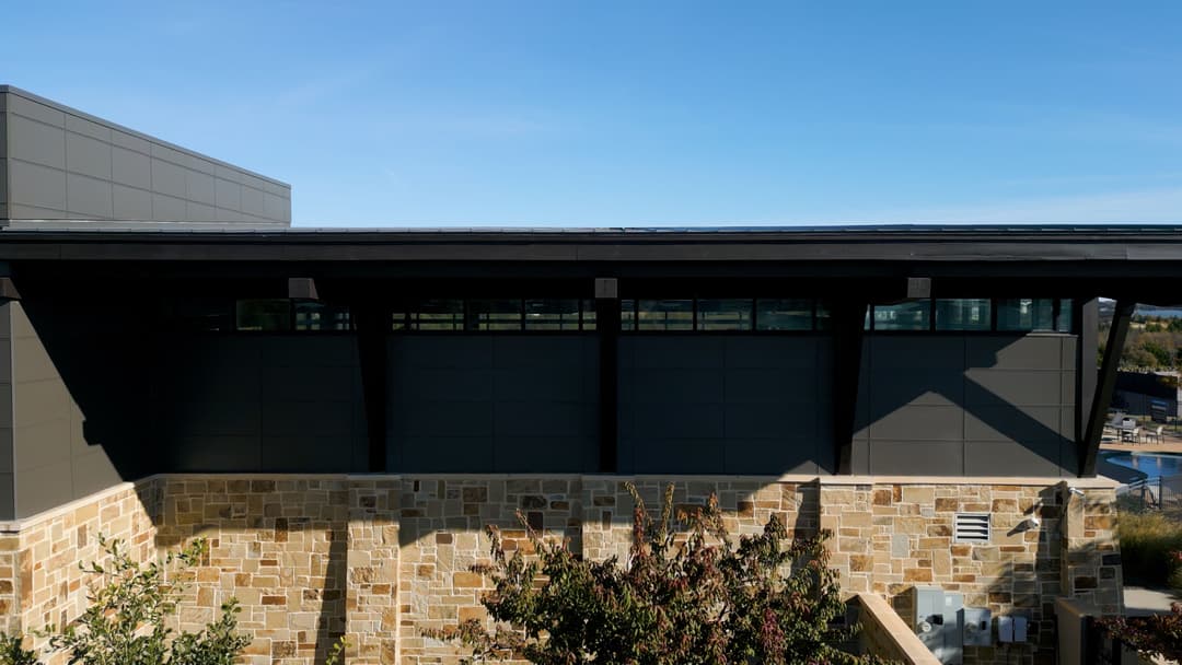 Modern building architecture with stone facade and large windows under a clear blue sky.