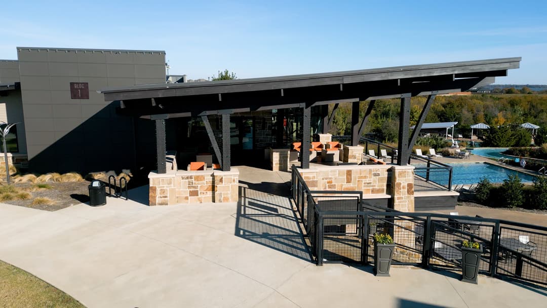 Modern poolside bar with outdoor seating, stone accents, and scenic views.