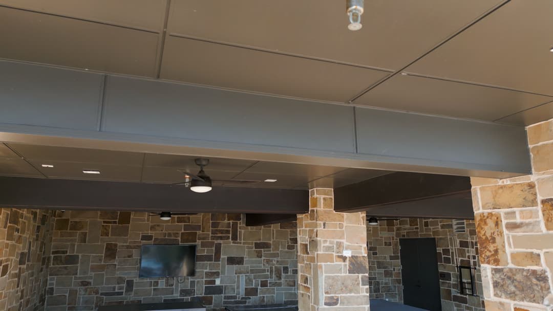 Stylish indoor space with stone walls, ceiling fan, and wall-mounted TV.
