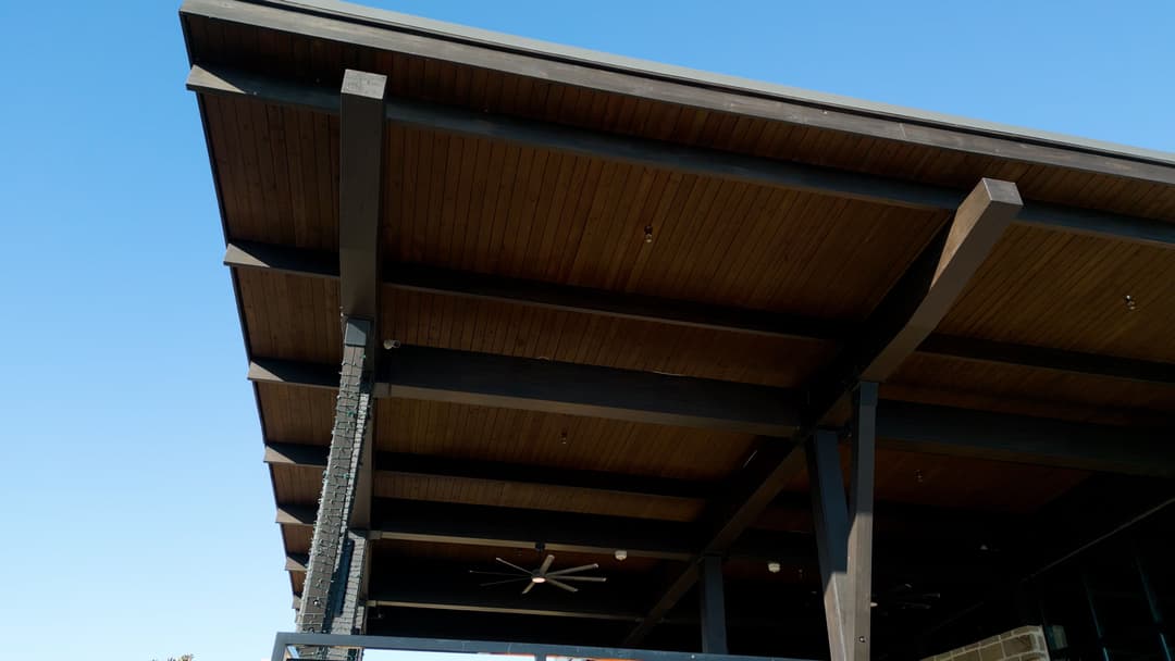 Modern architectural design featuring a wooden ceiling and exposed beams against a blue sky.