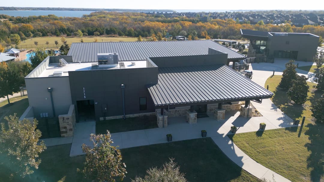 Modern community center with a sleek design, surrounded by landscaped grounds and trees.