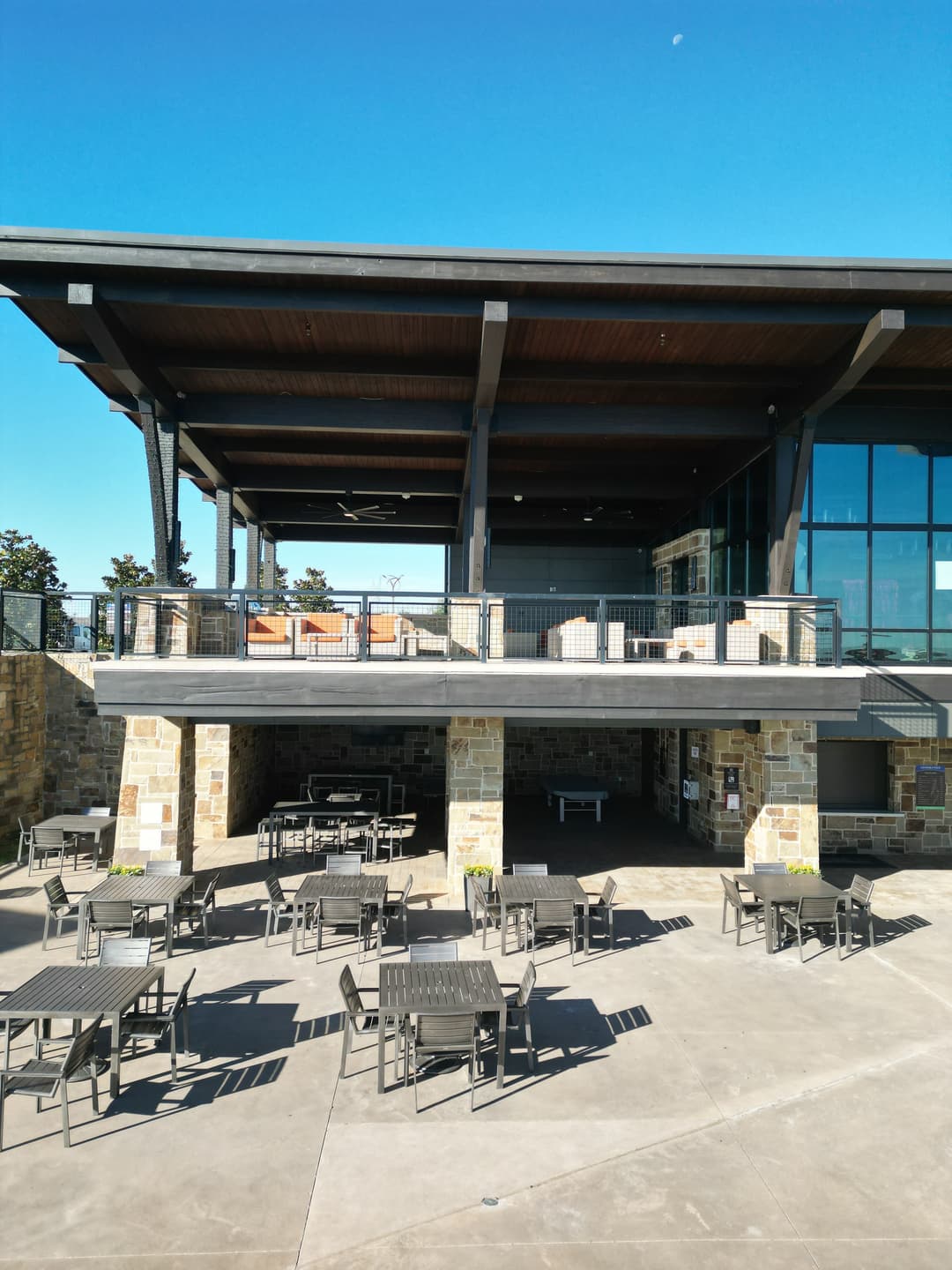 Modern building with outdoor seating area and stone accents under clear blue sky.