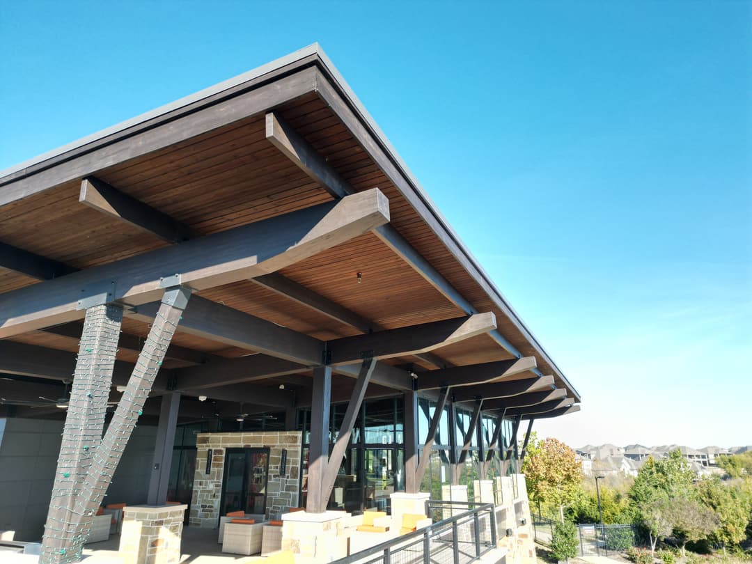 Modern architecture featuring a wooden overhang and stone accents against a clear blue sky.