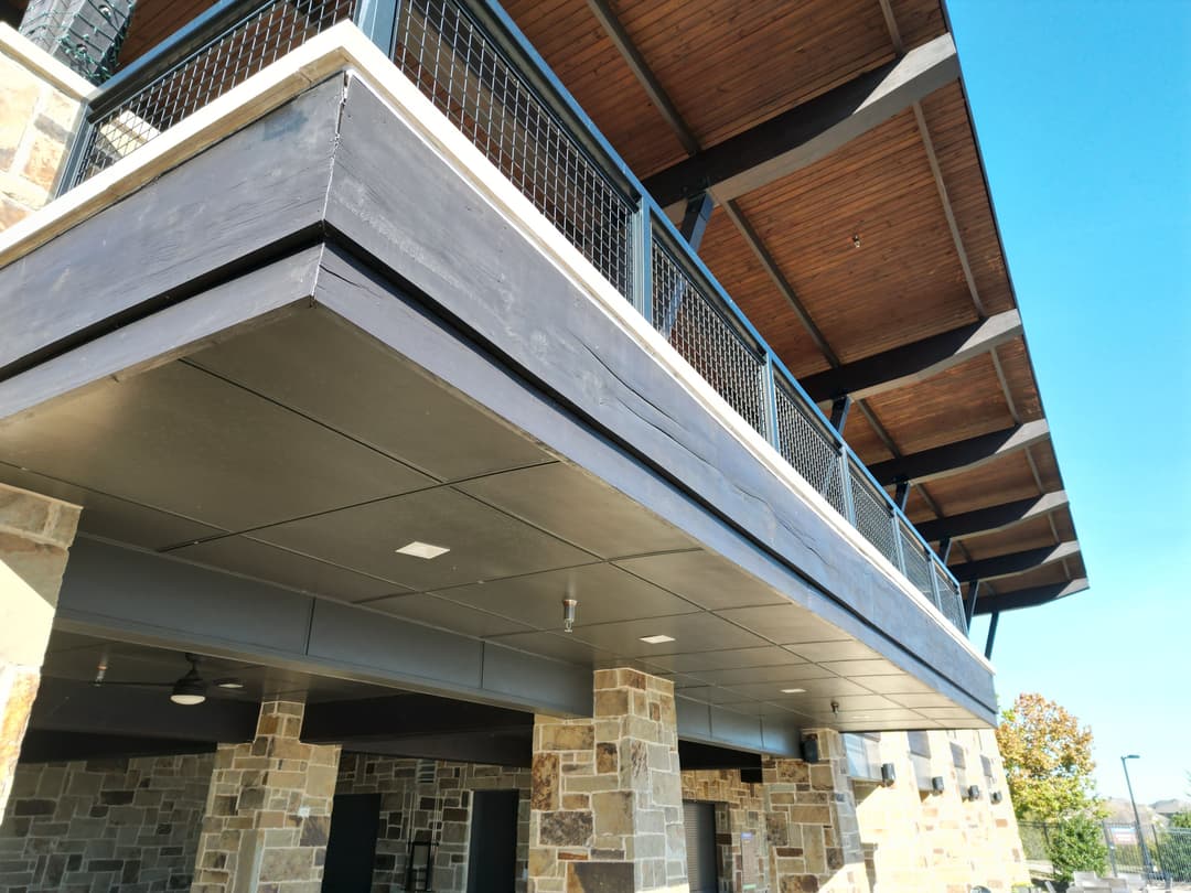 Modern building exterior showcasing wooden roof and stone walls under clear blue sky.