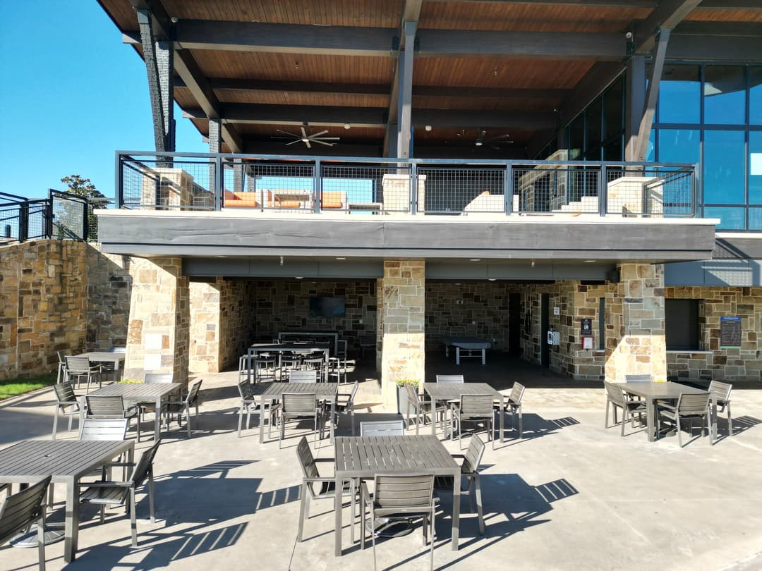 Modern outdoor patio area with empty tables under a stylish restaurant building.