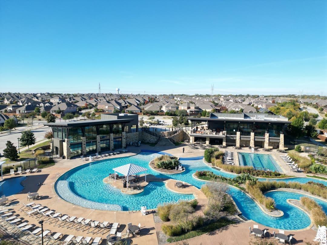 Luxury resort with pools and cabanas, surrounded by landscaped grounds and residential area.