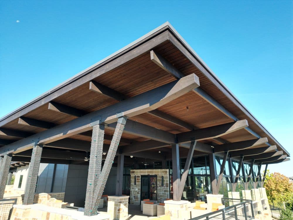 Modern building exterior with angled roof and wooden beams against clear blue sky.