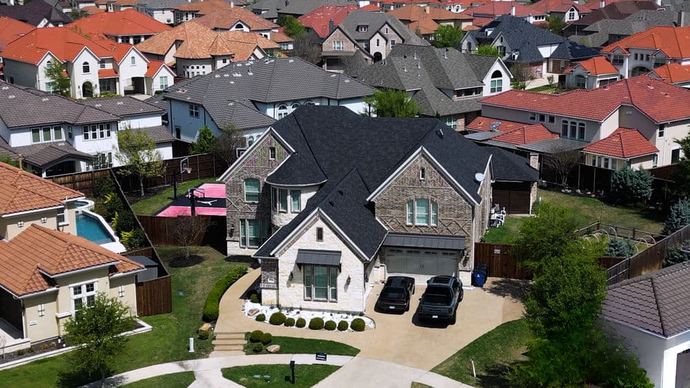 Aerial view of a commercial building with a flat roof, surrounded by parking and nearby structures.